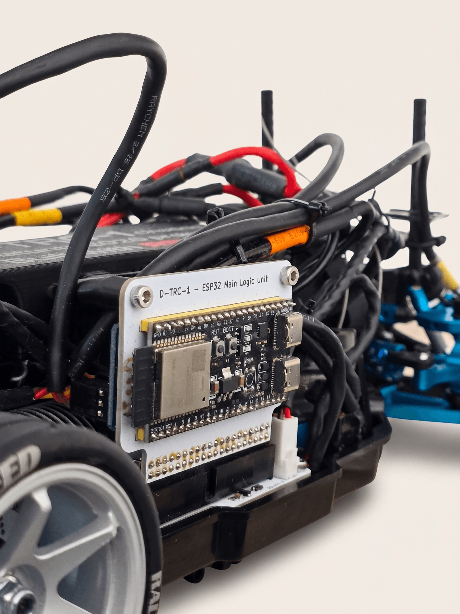 D-TRC-1 — vlastní ESP32 main logic unit nasazený v chassis, kabelový svazek a hliníkový rám viditelné v kontextu